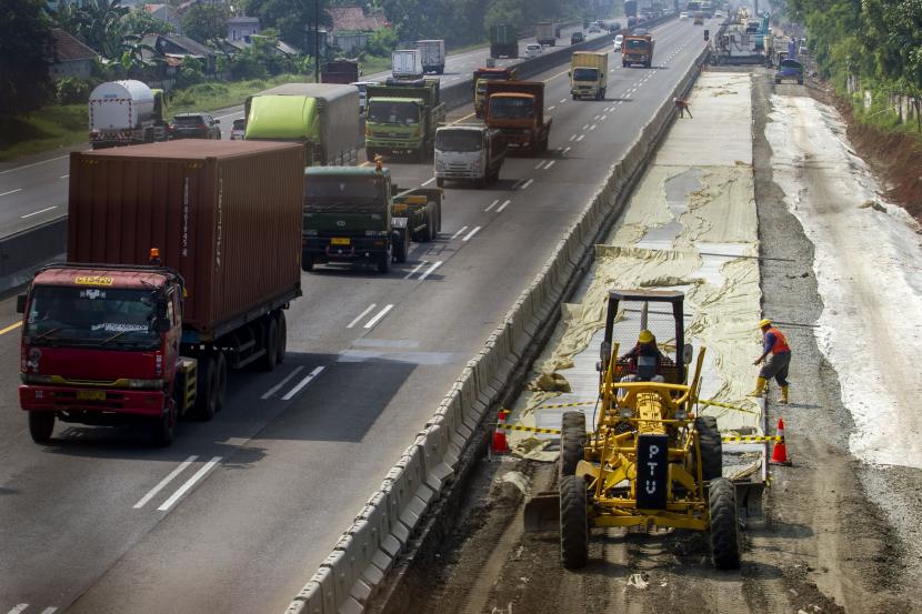 Pekerja mengoperasikan alat berat saat menyelesaikan proyek pelebaran jalan tol Jakarta-Cikampek di Kabupaten Karawang, Jawa Barat, Rabu (13/4/2022). 