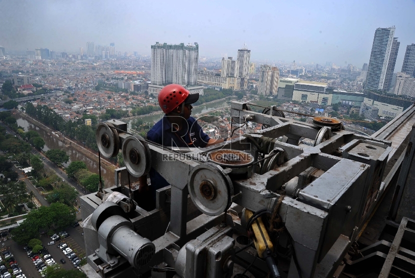  Pekerja mengunakan gondola saat melakukan perawatan gedung perkantoran di Sudirman, Jakarta, Senin (9/11).