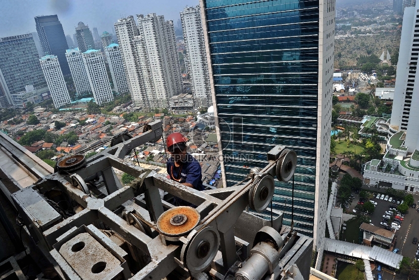 Pekerja mengunakan gondola saat melakukan perawatan gedung perkantoran di Sudirman, Jakarta, Senin (9/11). 