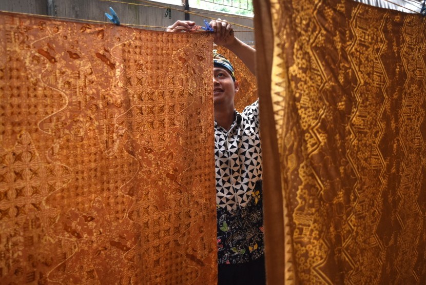 Pekerja menjemur kain batik yang telah diwarnai / Ilustrasi 