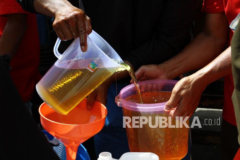 Pekerja menuangkan minyak goreng ke wadah milik warga. Pemkot Samarinda gelar operasi pasar minyak goreng curah.