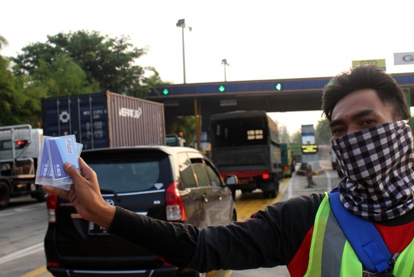 Pekerja menunjukkan kartu pembayaran elektronik tol (E-Toll) yang dijual di pintu gerbang Tol Cikunir, Bekasi, Jawa Barat, Rabu (11/10).