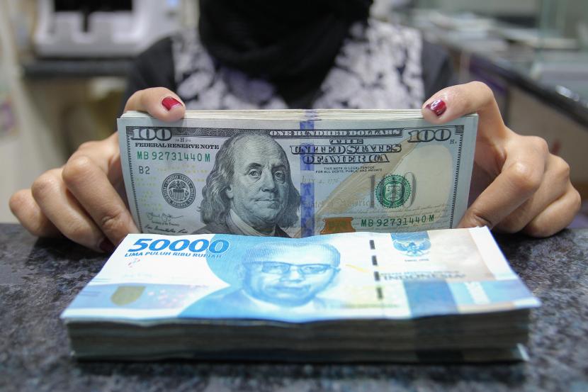 Pekerja menunjukkan uang dolar AS dan rupiah di salah satu gerai penukaran mata uang di Jakarta, Rabu (5/1/2022). 