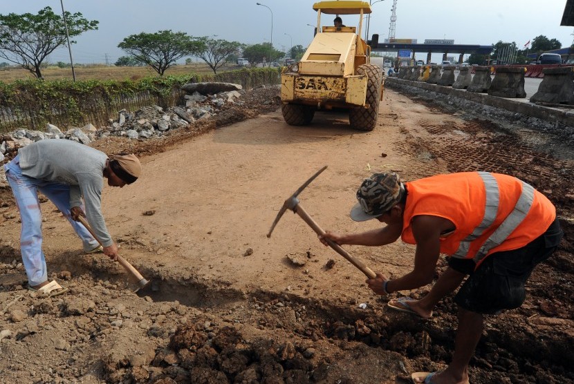 Pekerja menyelesaikan pekerjaan pelebaran lajur jalan pintu keluar-masuk gerbang tol Karawang Barat, di Karawang, Jawa Barat, Senin (9/11).