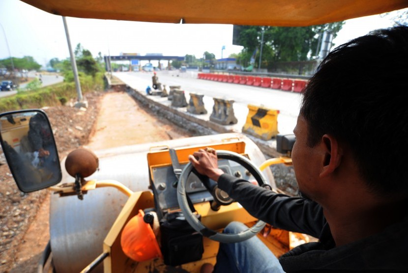 Pekerja menyelesaikan pekerjaan pelebaran lajur jalan pintu keluar-masuk gerbang tol Karawang Barat, di Karawang, Jawa Barat.