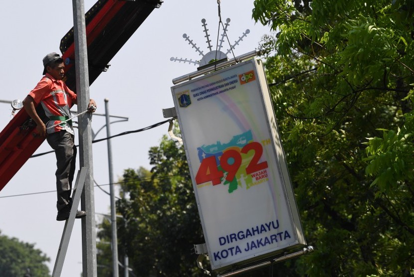 Pekerja menyelesaikan pemasangan lampu penerangan hias jelang HUT ke-492 Jakarta di jalan Medan Merdeka Utara Jakarta, Rabu (19/6/2019). 