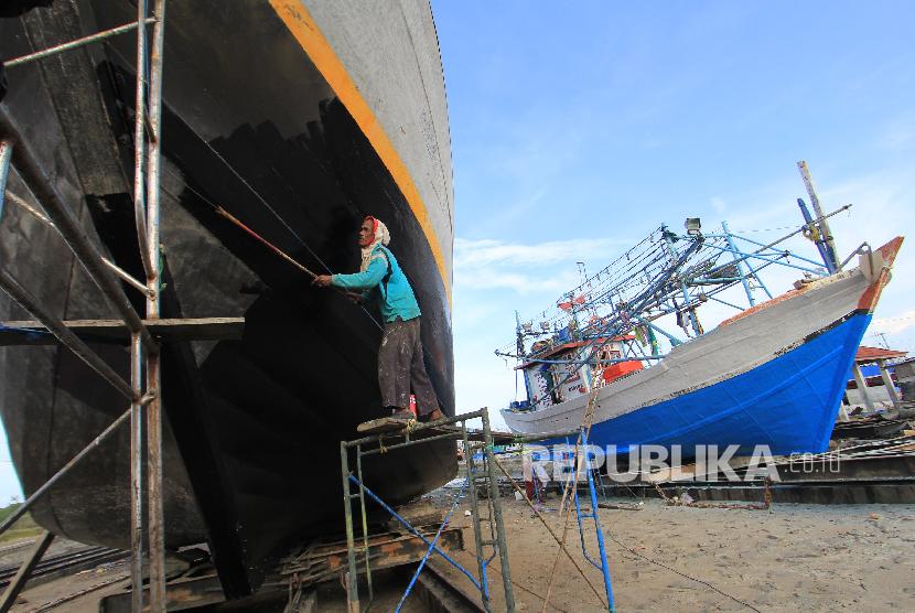 Pekerja menyelesaikan pengecatan kapal nelayan di Karangsong, Indramayu, Jawa Barat.