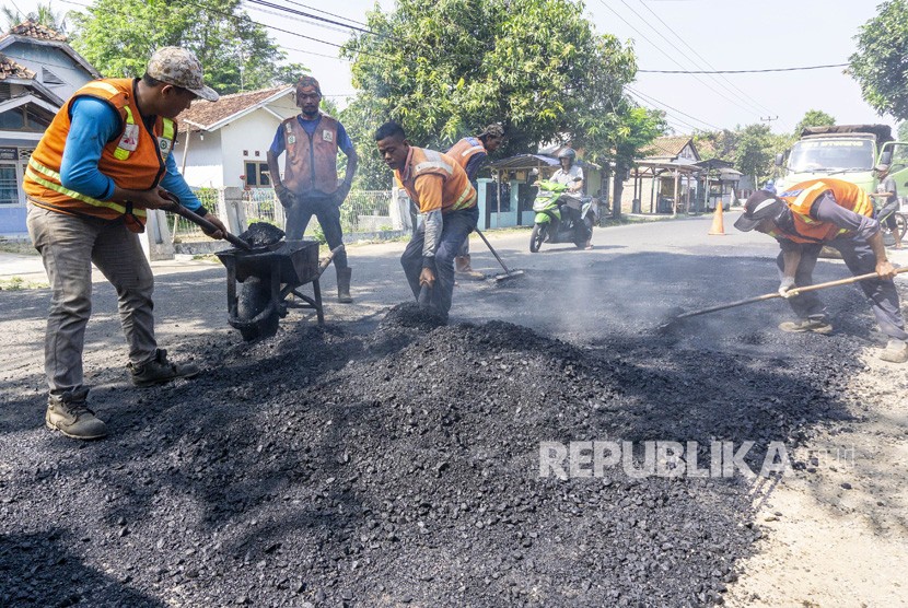 Pekerja menyelesaikan perbaikan jalan alternatif menuju jalur Pantura di jalan raya Cikalong - Cilamaya, Karawang, Jawa Barat, Rabu (15/5/2019).