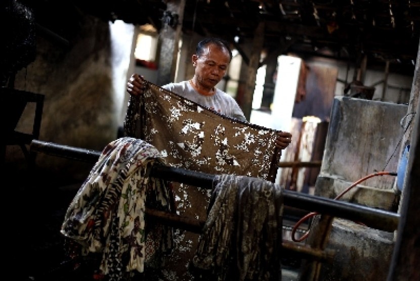 Pekerja menyelesaikan proses pewarnaan batik dengan bahan warna alami