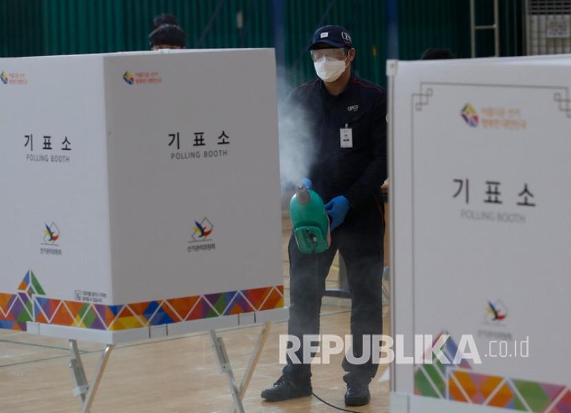 Pekerja menyemprotkan cairan desinfektan sebagai upaya pencegahan coronavirus di tempat pemungutan suara di Seoul, Korea Selatan, Selasa (14/4). Korea Selatan akan mengadakan pemilihan umum pada 15 April 2020.