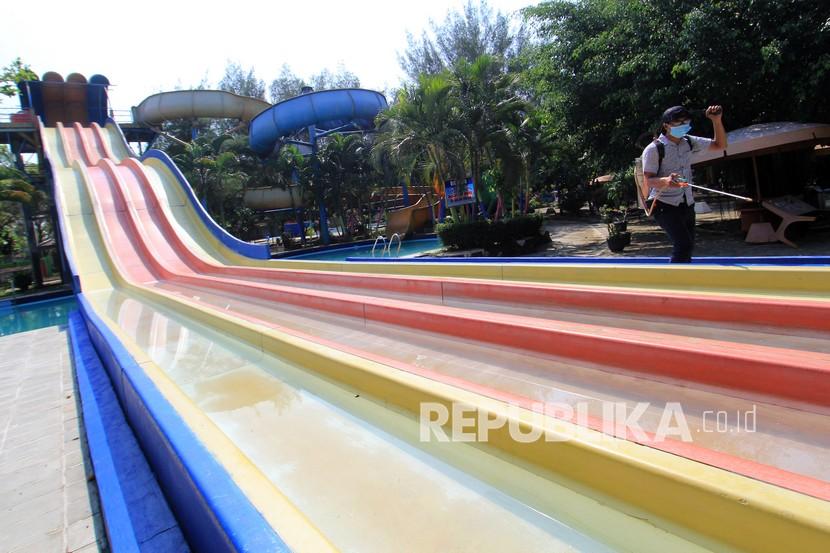 Pekerja menyemprotkan cairan disinfektan di kawasan objek wisata waterboom Bojongsari Indah, Indramayu, Jawa Barat, Ahad (16/5/2021). Pemda Indramayu menutup sejumlah objek wisata untuk mencegah terjadinya kluster COVID-19. 