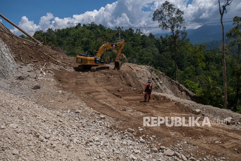 Pekerja menyingkirkan material longsoran yang memenuhi badan jalan poros Palu-Kulawi. Ilustrasi