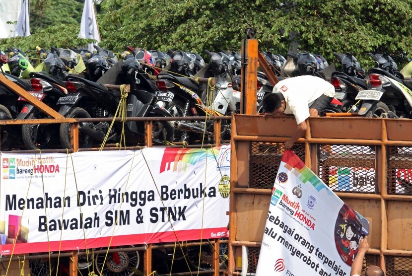 Pekerja merapihkan motor pemudik yang mengikuti kegiatan mudik bersama AHM, Jakarta, Ahad (20/7). AHM mengirim 980 motor secara gratis milik pengendara sepeda motor merek Honda yang akan mudik ke wilayah Semarang dan Yogya, sementara pengendara sepeda moto