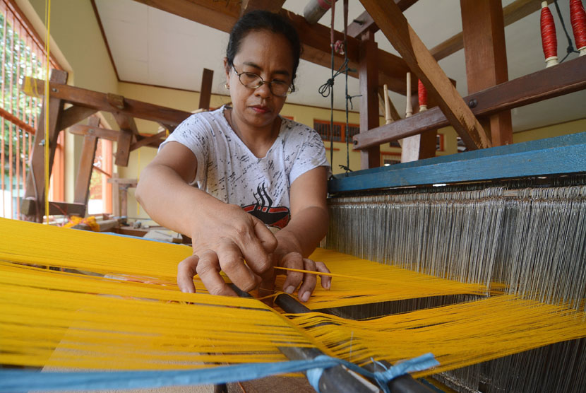 Pekerja merapikan bentangan benang kain Buya Sabe (sarung khas Donggala) yang ditenun di salah satu industri tenun rumah tangga di Palu, Sulawesi Tengah, Rabu (3/12).
