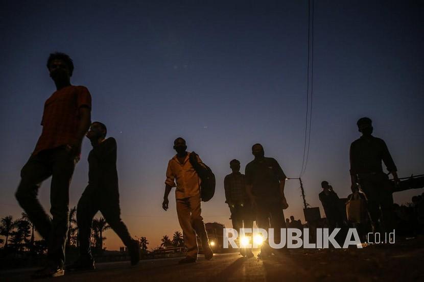 Pekerja migran menunggu transportasi untuk perjalanan pulang di jalan raya di pinggiran Mumbai, India, pertengahan Mei 2020 lalu. Ribuan pekerja migran kembali ke desa mereka setelah pemerintah India mengumumkan masa perpanjangan lockdown hingga akhir Mei.