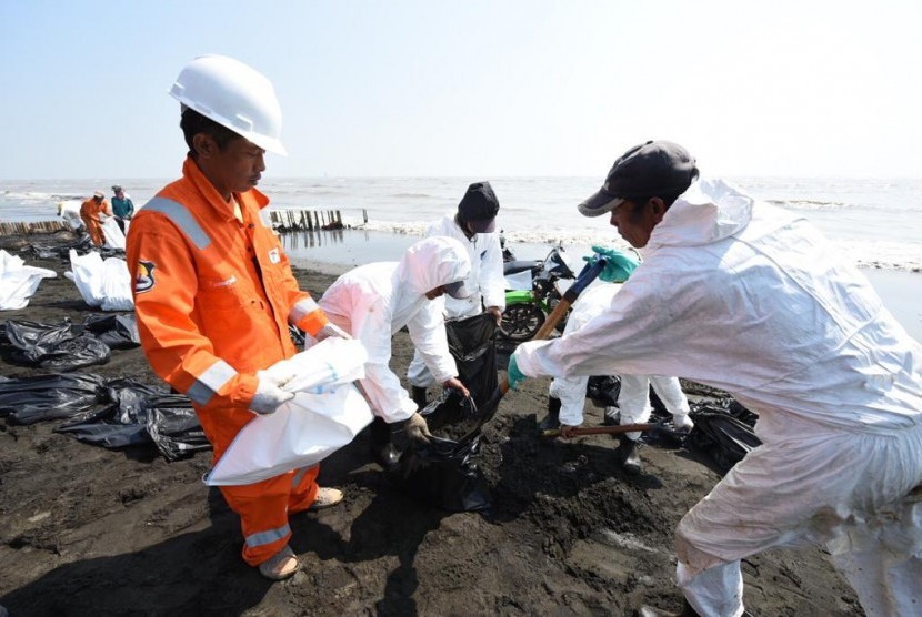 Pekerja Pertamina sedang membersihkan tumpahan minyak anjungan lepas pantai YY PHE ONWJ di wilayah Karawang, Jawa Barat.