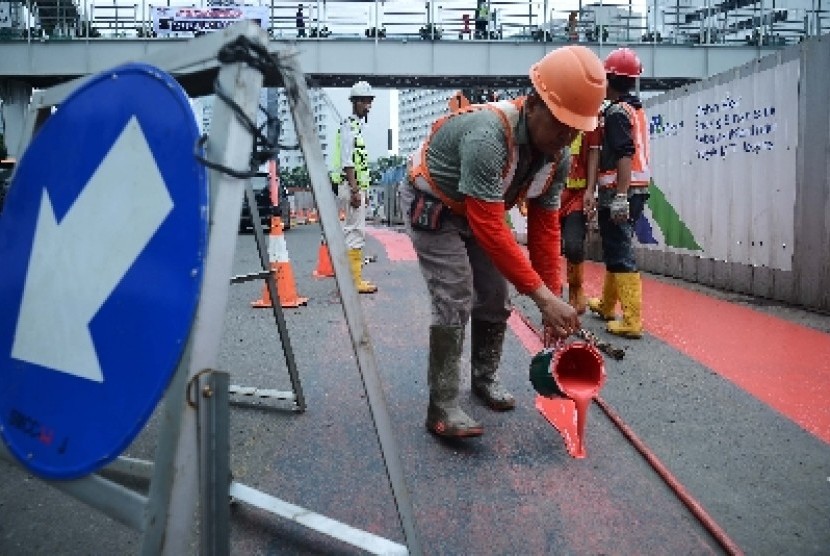 Pekerja proyek MRT Jakarta melakukan pengecatan jalur busway di Bundaran HI, Rabu (11/2).