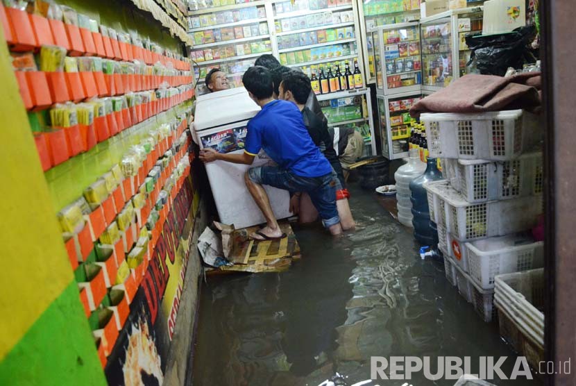 Pekerja sebuah toko membereskan barang dagangannya di lokasi banjir di Dayeuhkolot, Kabupaten Bandung, Ahad (13/3).   (Republika/Edi Yusuf)