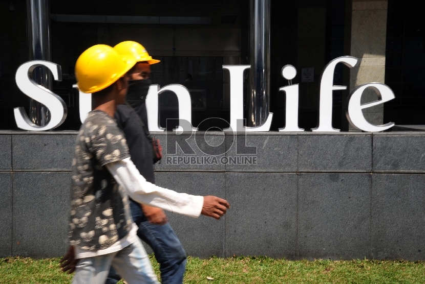 Pekerja sedang melintas didepan Menara Sunlife, Jakarta, Ahad (4/10). 