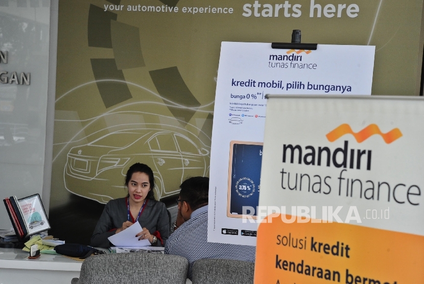 Pekerja sedang memberikan informasi kepada pengunjung di showroom mobil di Jakarta.