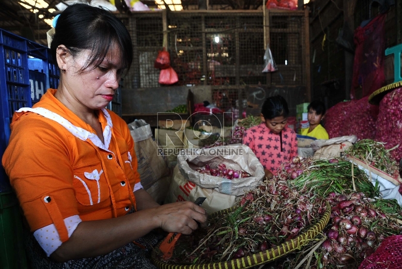 Pekerja sedang mengupas bawang merah di pasar Induk, Jakarta, Senin (14/12). 