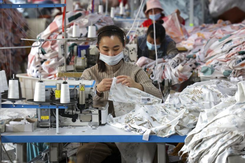 Pekerja yang memakai masker wajah menjahit kain di sebuah pabrik tekstil di daerah Huimin di provinsi Shandong, China timur pada 25 Oktober 2022. Pembukaan kembali China setelah pembatasan covid-19 berakhir berhasil mengerek konsumsi dan mendorong PDB China sehingga IMF menaikkan prospek pertumbuhan ekonomi Asia jadi 4,6 persen dari 4,3 persen.