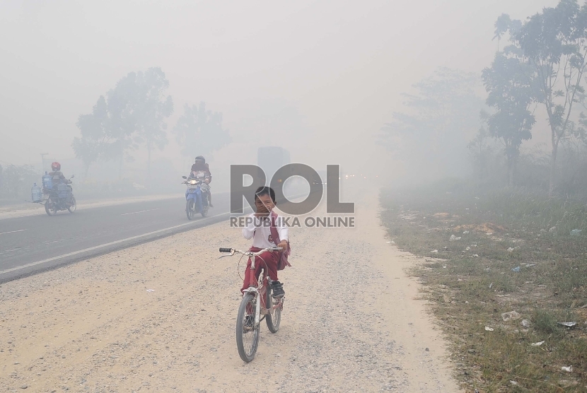 Pelajar berjalan menembus kabut asap di kawasan Rimbo Panjang, Tambang, Kampar, Riau, Selasa (1/9). Akibat Kabut asap kebakaran lahan gambut, sudah mulai menggangu lalu lintas jalan karena jarak pandang yang terbatas.