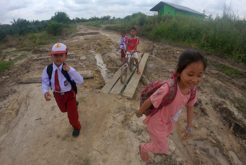 Pelajar kelas jauh SDN 04 Timpeh melintasi jalan desa yang rusak parah di Kampung Jao, Panyubarangan, Dharmasraya, Sumatera Barat. Dharmasraya dilanda banjir bandang hingga longsor pada Ahad (31/10). Peristiwa yang terjadi pada malam hari itu kini telah surut dan dilaporkan dua rumah mengalami kerusakan.