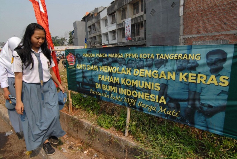Pelajar melintas di dekat spanduk penolakan paham komunis di daerah Ciledug, Tangerang, Banten, Kamis (1/10). 