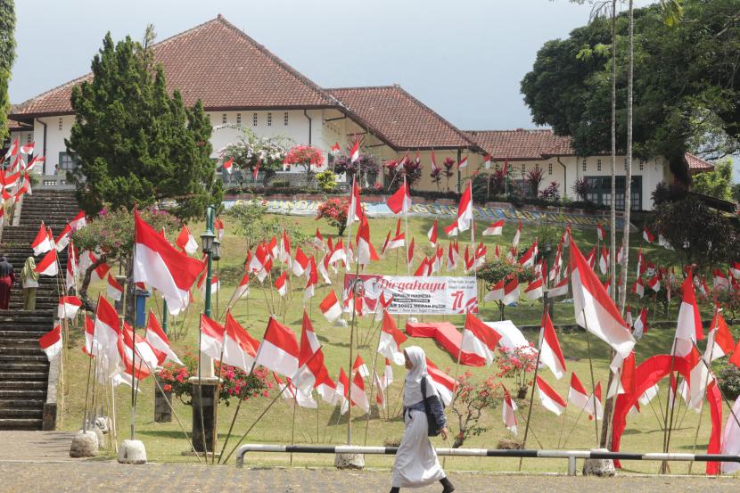 Pelajar melintasi halaman Gedung Perundingan Linggarjati yang berhias 10.001 Bendera Merah Putih di Kuningan, Jawa Barat, Kamis (11/8/2022). Pemasangan 10.001 Bendera Merah Putih tersebut dalam rangka menyambut perayaan HUT ke-77 Kemerdekaan RI.