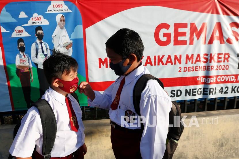 Pelajar membenahi masker adiknya pada hari pertama sekolah tatap muka di SD Negeri 42, Banda Aceh, Aceh, Senin (4/1). Berdasarkan analisis data Satgas Penanganan Covid-19, tren kasus positif Covid-19 di semua tingkatan anak usia sekolah meningkat. (ilustrasi) 