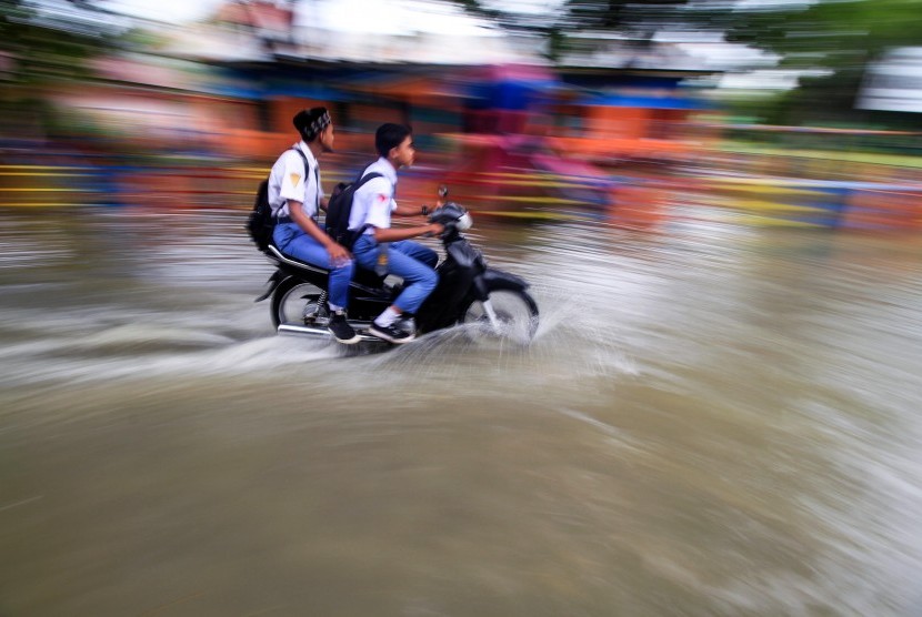 Pelajar menerobos genangan banjir.