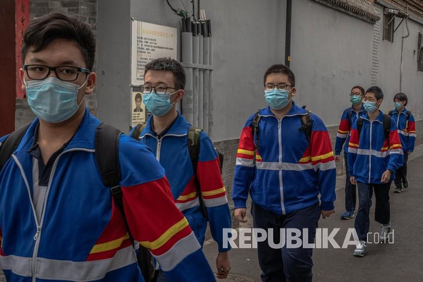 Pelajar menggunakan masker saat meninggalkan sekolah menengah pada hari pertama sekolah di Hutong, Beijing, Cina, Senin (11/5). Beijing akan mulai mencabut sebagian besar larangan keluar-masuk warga dari Wuhan. Ilustrasi. 