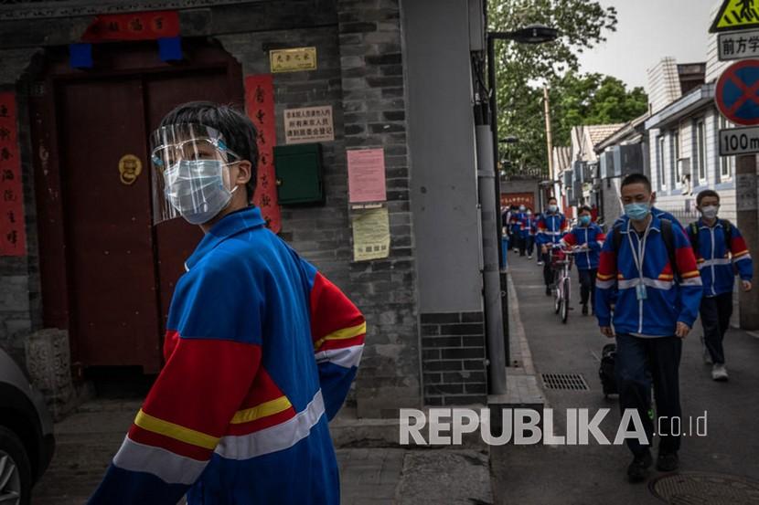 Pelajar menggunakan masker saat meninggalkan sekolah menengah pada hari pertama sekolah di Hutong, Beijing, Cina, Senin (11/5). Sekolah menengah di Beijing kembali dibuka untuk pertama kalinya setelah penutupan aktivitas belajar di sekolah pada Januari karena wabah coronavirus dan penyakit COVID-19.  
