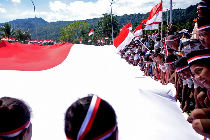 Pelajar perbatasan RI-PNG membentangkan bendera merah putih di perbatasan Skouw-Wutung, Republik Indonesia - Papua New Guinea (PNG), Rabu (30/11).