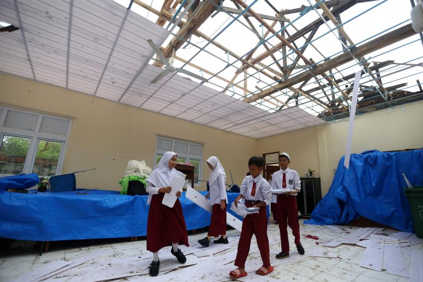 Pelajar membenahi berkas dan alat tulis di ruangan guru yang atapnya rusak akibat bencana angin kencang. Sebanyak 2.906 sekolah di Provinsi DIY berada di kawasan rawan bencana.