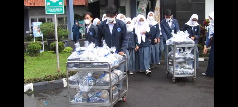 Pelajar SMKN 9 Bandung membagikan rantang siswa berbagi dengan masyarakat kecil.