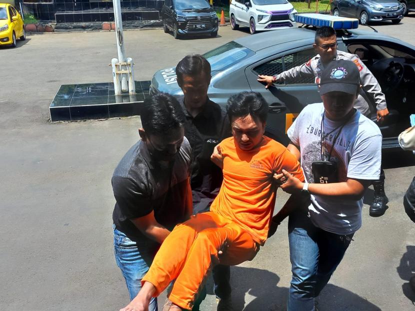 Pelaku pembunuhan sadis di Rancasari, Kota Bandung Budi Alias Kadal tengah dibopong oleh petugas kepolisian di Mapolrestabes Bandung, Kamis (12/1/2023). Korban ditembak di bagian kaki kiri karena sempat melakukan perlawanan. 