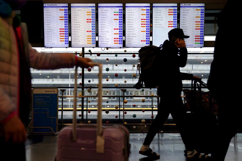 Pelancong berjalan di depan layar informasi penerbangan American Airlines di Bandara Internasional OHare, Illinois, Chicago, AS. Amerika Pertimbangkan Pembatasan Kedatangan Warga China