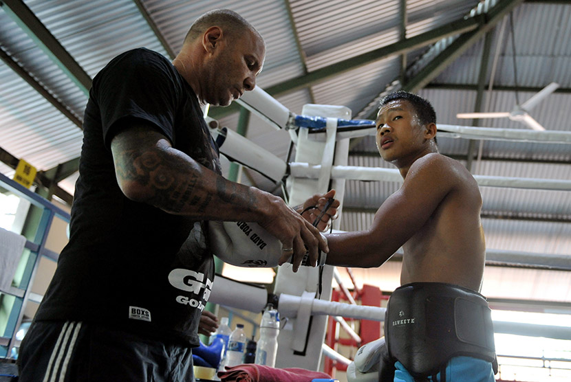 Pelatih Craig Christian (kiri) memasangkan sarung tinju pada petinju Daud Yordan saat latihan di Kuta, Bali, Rabu (6/1).