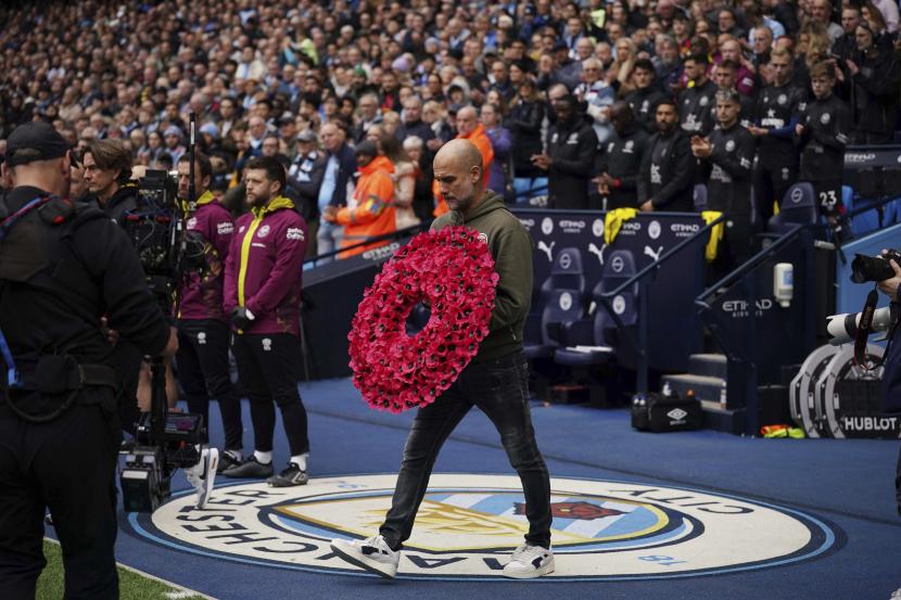  Pelatih kepala Manchester City Pep Guardiola memegang bunga untuk Remembrance Day, sebelum dimulainya pertandingan sepak bola Liga Inggris antara Manchester City dan Brentford, di stadion Etihad di Manchester, Inggris, Sabtu, 12 November 2022. 