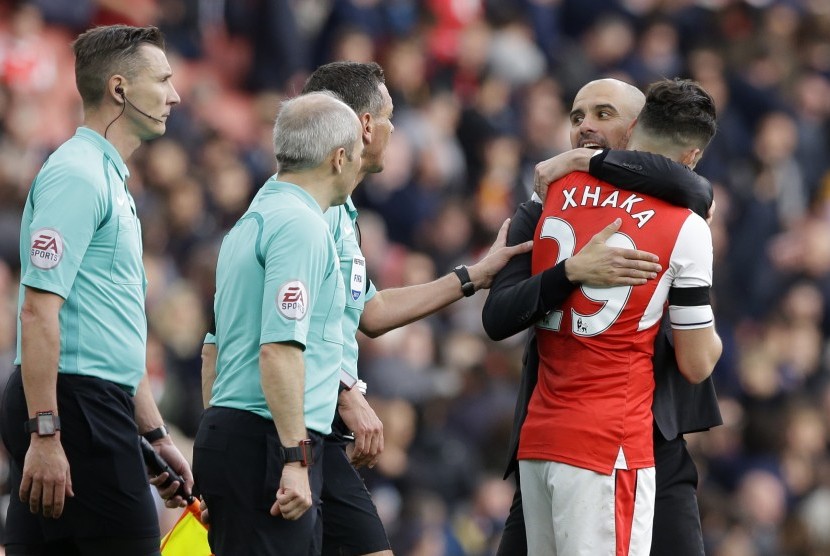 Pelatih Manchester City, Pep Guardiola memeluk gelandang Arsenal, Granit Xhaka seusai laga Liga Primer di stadion Emirates, Ahad (2/4). Laga berakhir imbang 2-2.