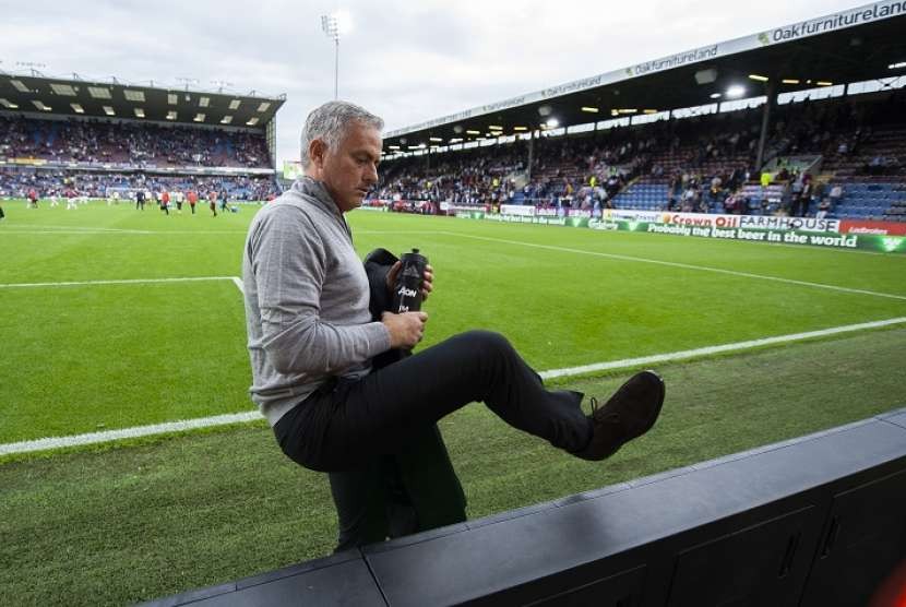Pelatih Manchester United Jose Mourinho melompati papan iklan sebelum memberikan tempat minum dan mantelnya kepada fan Iblis Merah seusai laga melawan Burnley, Ahad (2/9).