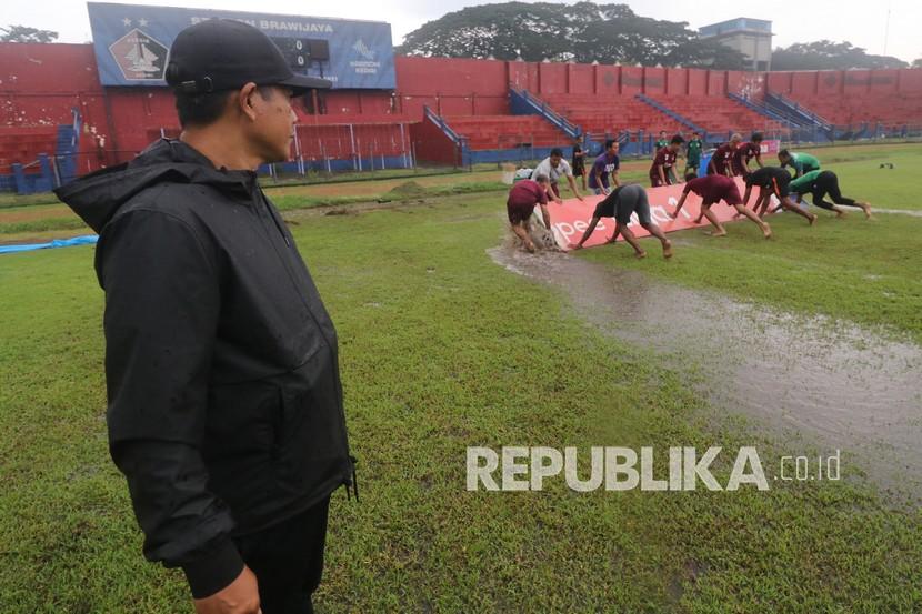Pelatih Persik Kediri Joko Susilo (kiri) mengamati proses pengeringan lapangan menggunakan papan di Stadion Brawijaya, Kota Kediri, Jawa Timur, beberapa waktu lalu.
