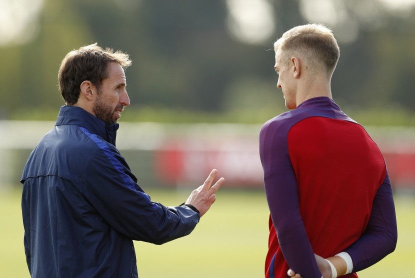 Pelatih timnas Inggris, Gareth Southgate (kiri) berbincang dengan kiper, Joe Hart saat sesi latihan di London, Senin (10/10).