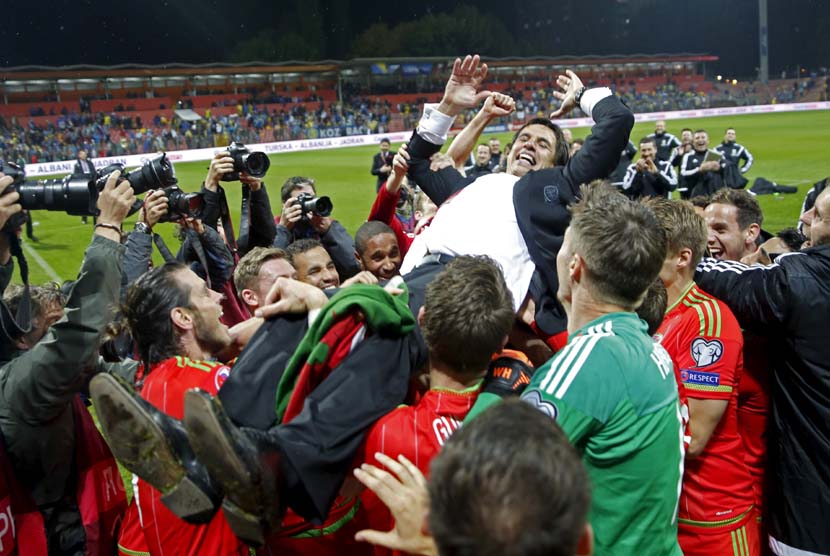 Pelatih Timnas Wales, Chris Coleman, melakukan selebrasi bersama pemainnya usai lolos ke putaran final Piala Eropa 2016 setelah mengalahkan Bosnia di Zenica pada Sabtu (10/10). 