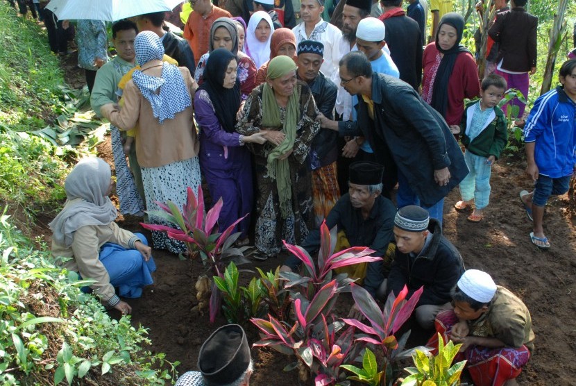 Pelayat dan keluarga memanjatkan doa seusai prosesi pemakaman seorang korban dugaan keracunan makanan massal, Didin Samsudin (58) di Desa Girijaya, Nagrak, Sukabumi, Jawa Barat, Selasa (19/1). 