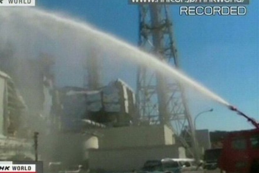 Pemadam kebakaran menyemprotkan air ke reaktor nomer 3 di PLTN Fukushima.