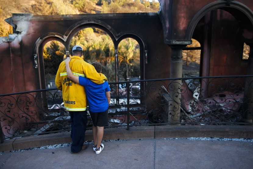 Pemadam kebakaran Terry Sanders dan putranya Isaac kehilangan rumahnya akibat kebakaran. Mereka melihat rumah tetangga yang juga terbakar di Santa Rosa, California, (14/10).