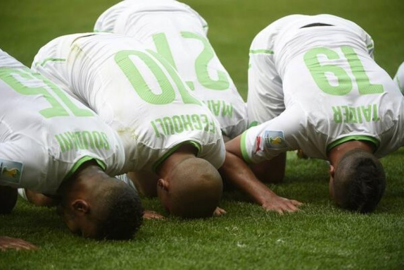 Pemain Aljazair merayakan gol dengan sujud syukur di pinggir lapangan.